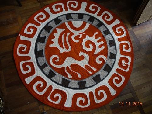 Round red and white rug with snow leopard and ibex motifs.