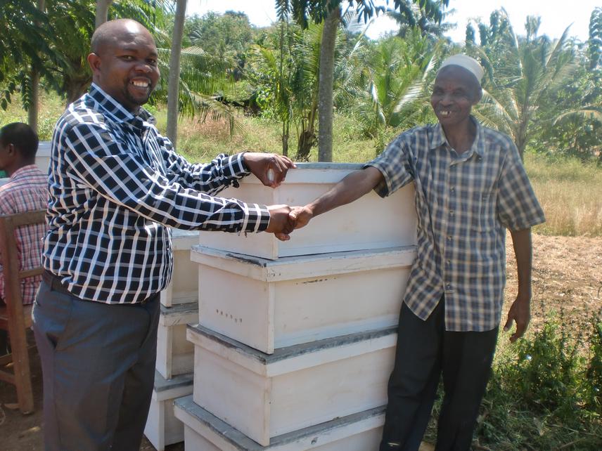 The grantee handing over beehives to the Chairman of  Mapatano bee keeping group.