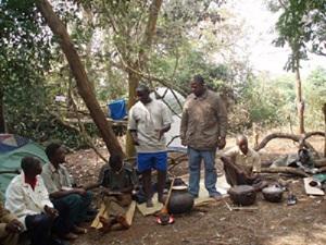 Mburu (standing in blue shorts) developing the traditional ecological learning process youth in a forest.